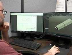 Engineer at computer looking at 3D model.